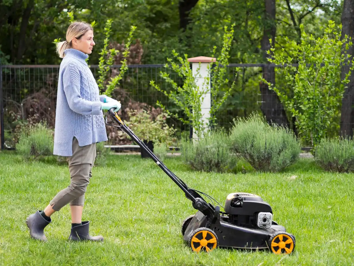 Czech man cleaning lawn mower carburetor backyard