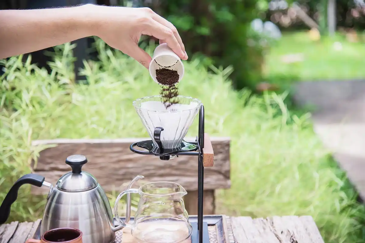 hand spreading coffee grounds on grass Czech garden