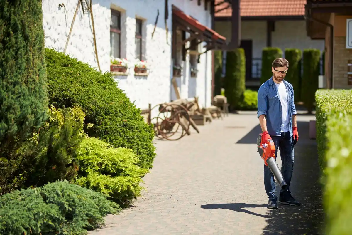 czech man using battery grass trimmer in small backyard