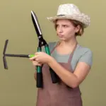 young Czech gardener using hand cultivator tool in allotment garden