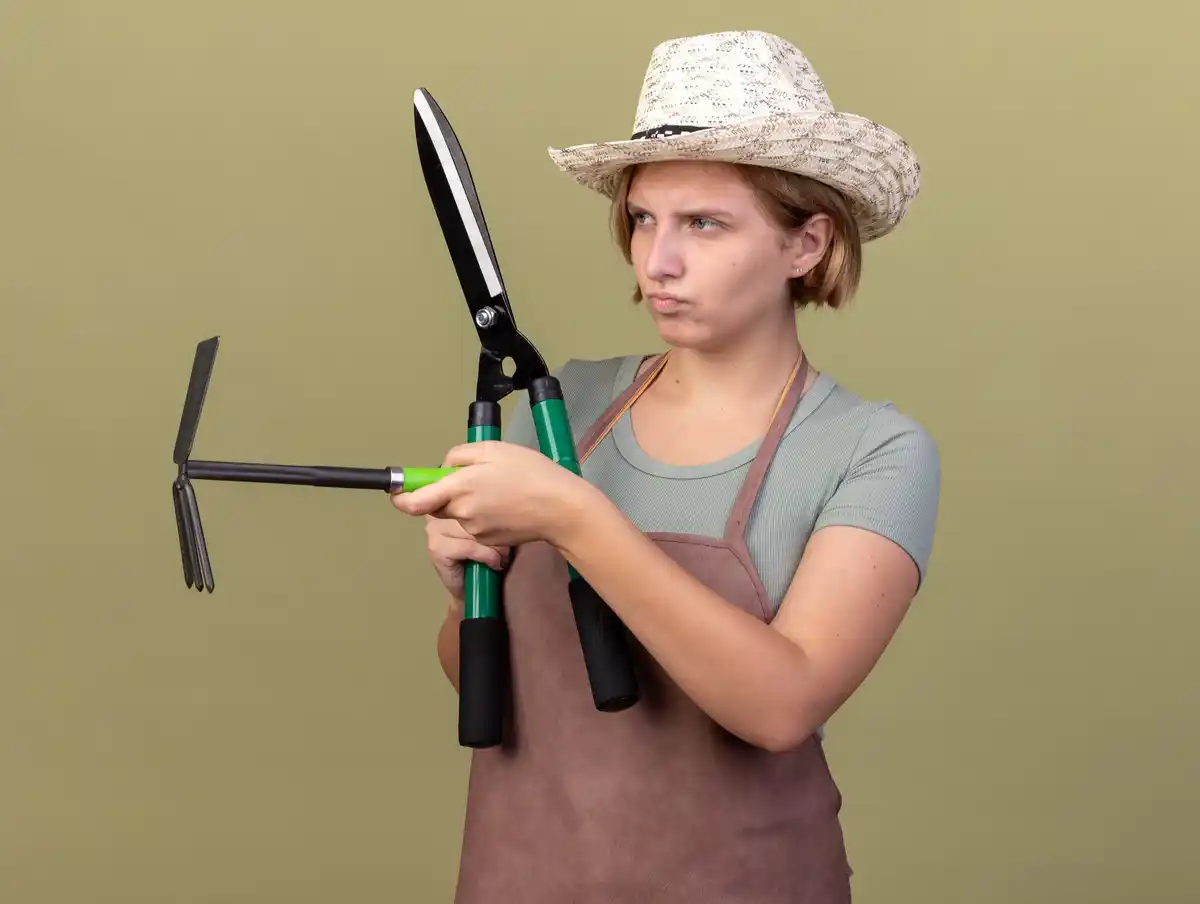 young Czech gardener using hand cultivator tool in allotment garden